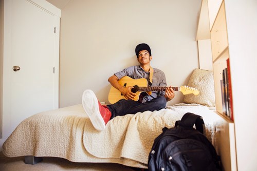 Pojke som sitter i en säng med en gitarr